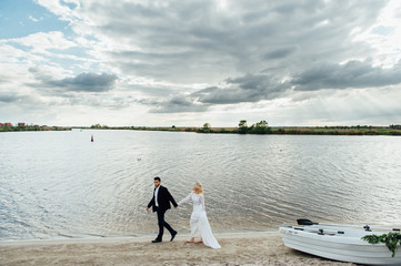 Bride and groom walking near the boat at river