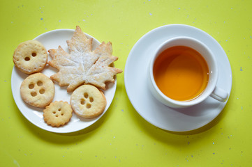 cookies and cup of tea on green background