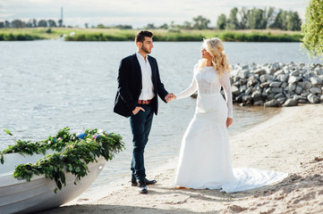 Bride and groom walking near the boat at river