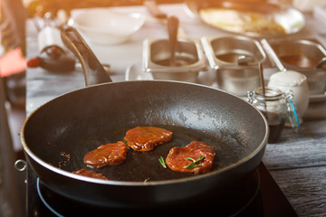 Meat with herb on pan. Dark meat on frying pan. Veal cooked with whole pepper. Juicy meat medallions.