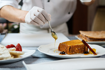 Spoon pouring honey on plate. Plate with piece of cake. Delicious honey cake with decoration. Creating new design for dessert.