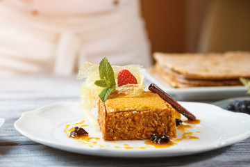 Cake on white plate. Raspberry on top of cake. Honey cake and mint leaf. Dessert worth a try.