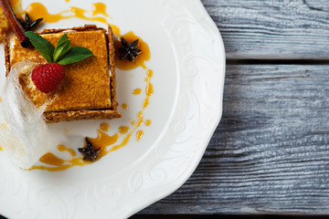 Cake decorated with mint leaf. Fresh cake on white plate. Honey cake on the table. Finest dessert from restaurant menu.
