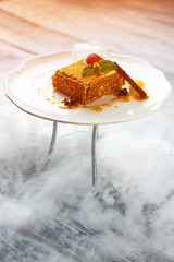 Plate with cake under sunlight. Mint on top of cake. Design of traditional honey cake. Combination of taste and style.