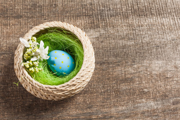 Easter eggs in nest on color wooden background