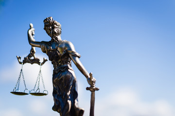 back of sculpture of themis, femida or justice goddess on bright blue sky copyspace background