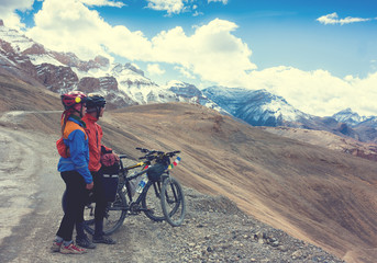 Happy cyclist couple standing on mountains road. Himalayas, Jammu and Kashmir State, North India 
