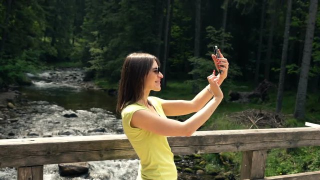 Young woman on bridge taking selfie photo by river, super slow motion 240fps
