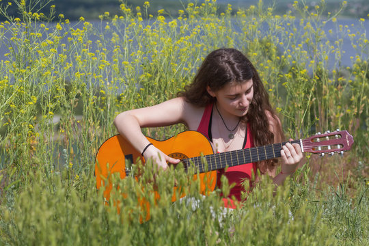 Cute female Musician sitting on green Grass