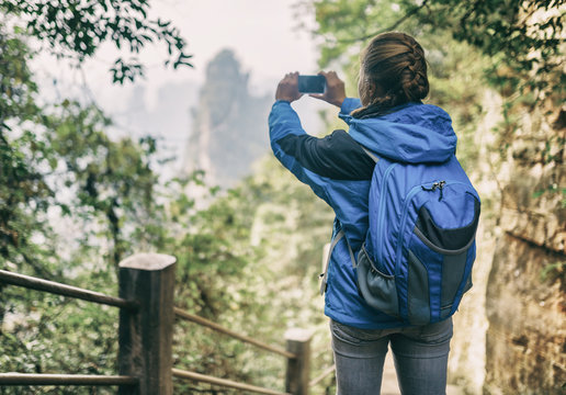 Female tourist taking photo of scenic mountain. Toned image