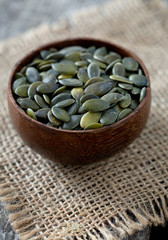 pumpkin seeds in a bowl over wooden surface