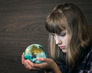 Girl looks at a glass ball in his hands. The concepts and ideas - the planet earth, magic, watch, study. Ecology, Clean Planet