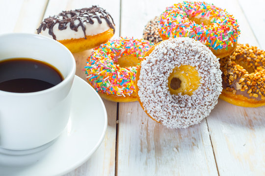 Donuts and coffee on a white wood background.