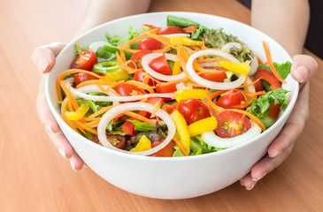 Woman showing fresh salad bowl - healthy eating