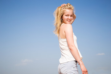 Sweet blonde young girl resting on a beach in a sunny morning