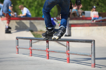 Aggressive inline rollerblader grinding on rail in skatepark