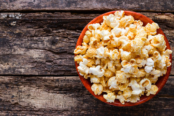 Popcorn in a bowl on a wooden background with space for text