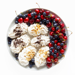 meringue and fresh ripe fruit. blueberries and cherries. on whit