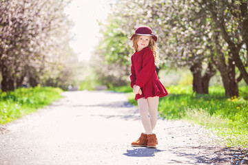 Outdoor portrait of adorable smiling little girl in dress and hat