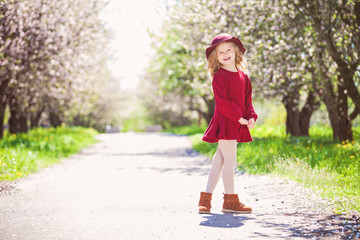 Outdoor portrait of adorable smiling little girl in dress and hat