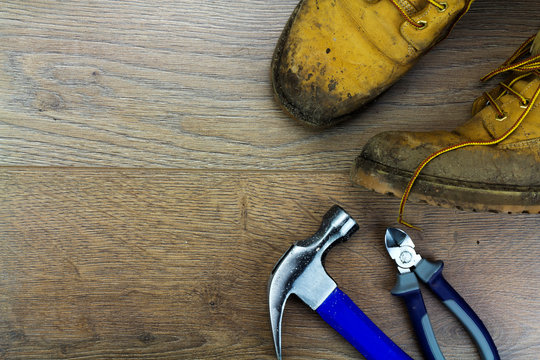 Muddy work boots and tools on a wooden floor