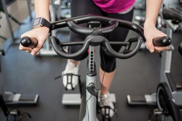 Fototapeta na wymiar Woman working out on exercise bike at spinning class