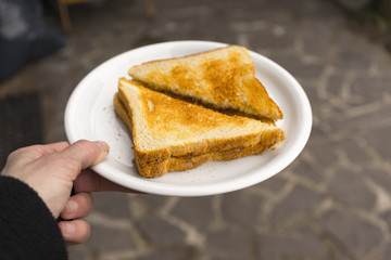 First person perspective of grilled cheese sandwich cut in half diagonally and set in a foam plate