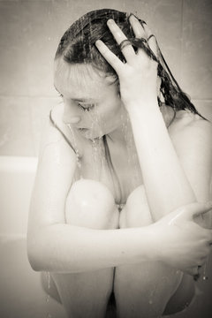 black and white portrait of looking depressed and crying emotional blond young beautiful lady relaxing in bath shower