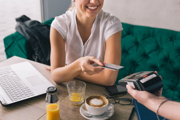 Woman pay with credit card in cafe bar