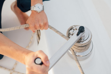 hands of man on a yacht pulling rope