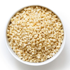 Bowl of peeled chopped almonds isolated on white from above.