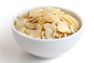 White bowl of peeled flaked almonds isolated on white.