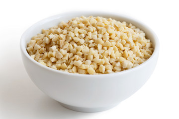White bowl of peeled chopped almonds isolated on white.