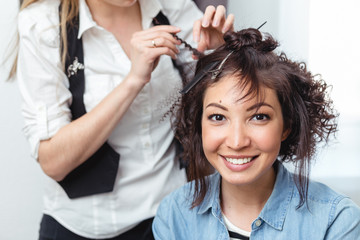 Beautiful woman having her hair curled in barber salon