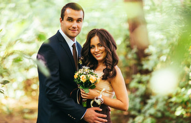happy groomsman and bridesmaid having fun and laughing in forest with pine tree