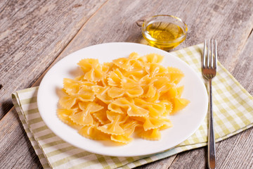 Farfalle on a white plate on wooden background