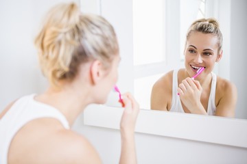 Obraz na płótnie Canvas Young woman brushing teeth in bathroom