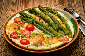 Fried eggs with green asparagus and tomatoes.