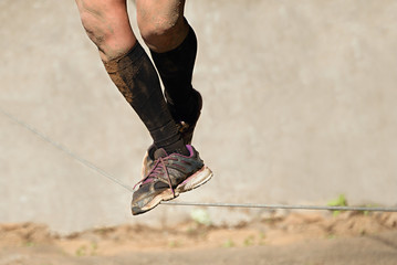 Man walking a tightrope at the mud raceVisible only legs