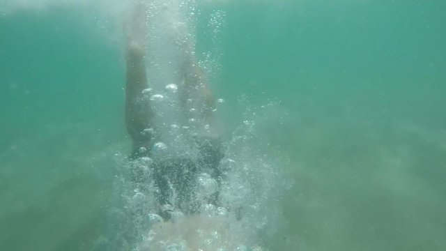 Slow motion of a man diving underwater and swimming in the sea.