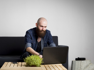 Young bearded man using a laptop at home.