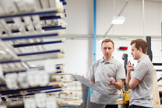 Manager examining fabric with worker in roller blind factory