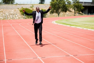 Fototapeta premium Excited businessman standing on the running track