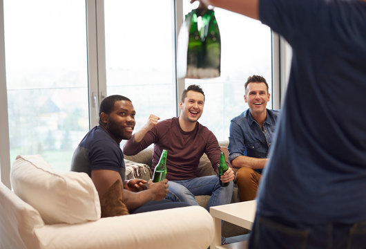 Rear view of man showing smiling friends beers