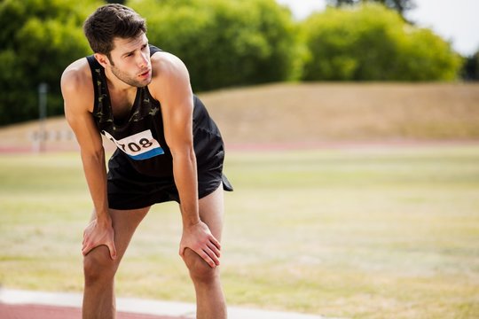 Tired athlete standing on running track