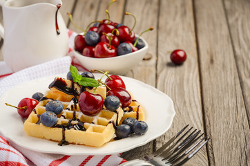Waffles with chocolate sauce, cherries and blueberries, selective focus, copy space