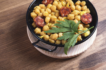 Close-up of delicious chickpea cereal with codfish and cut sausage,decorated with parsley.From above
