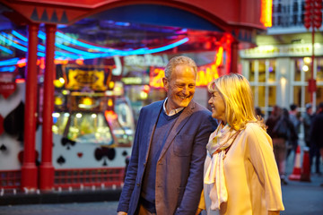 Mature dating couple strolling on city street at night, London, UK
