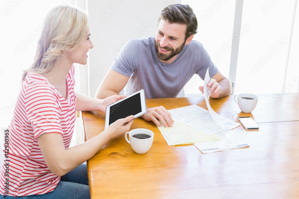 Poster couple looking at each other while using digital tablet
