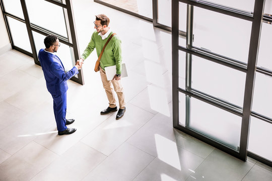 High angle view of businessmen shaking hands at office entrance